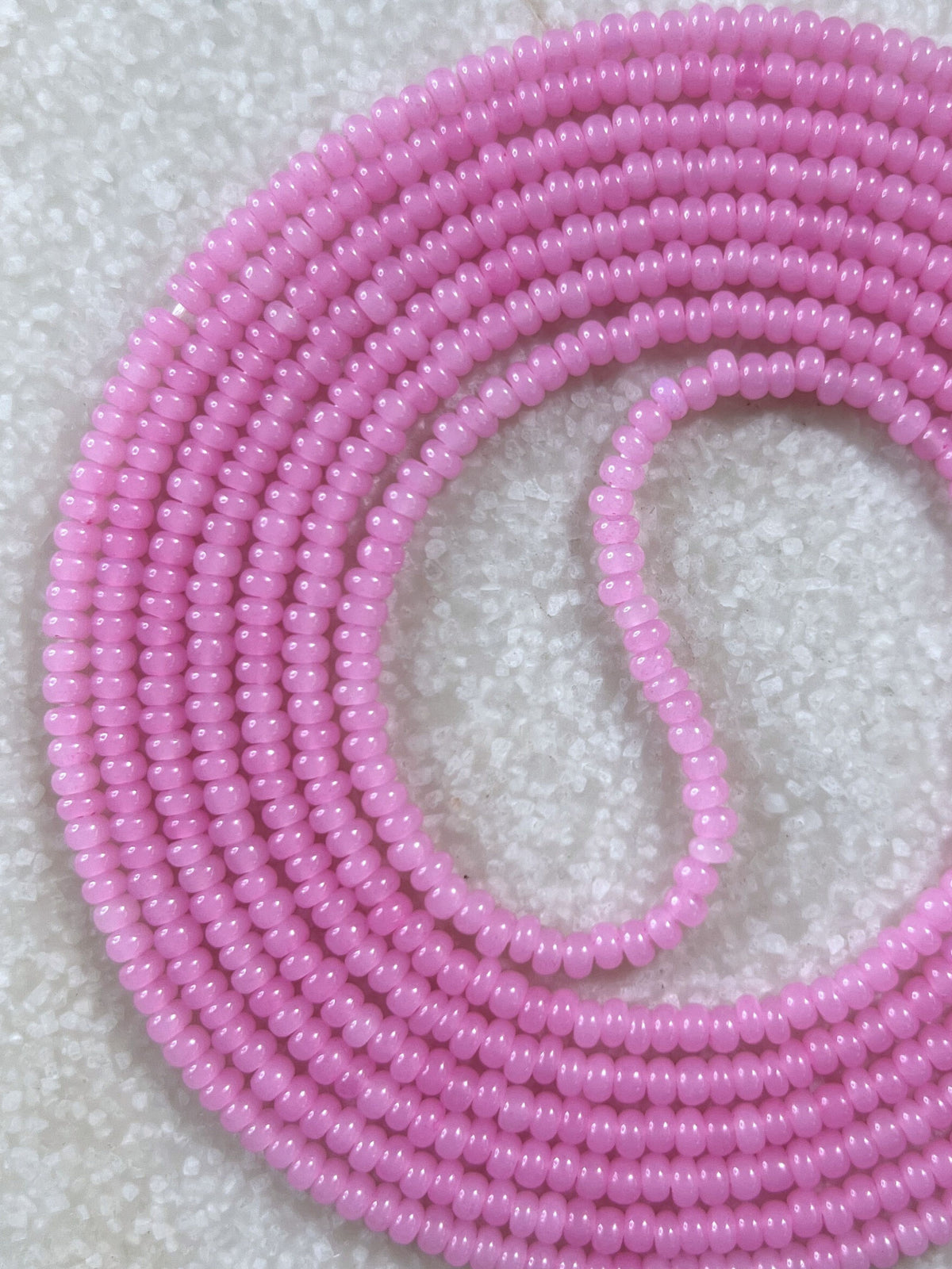 A coiled strand of pink beads arranged in a circular pattern.
